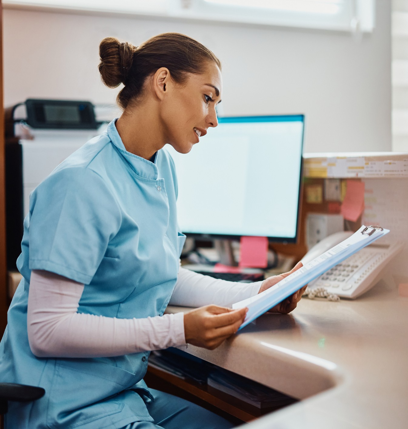 Nurse reviewing documents at a desk.